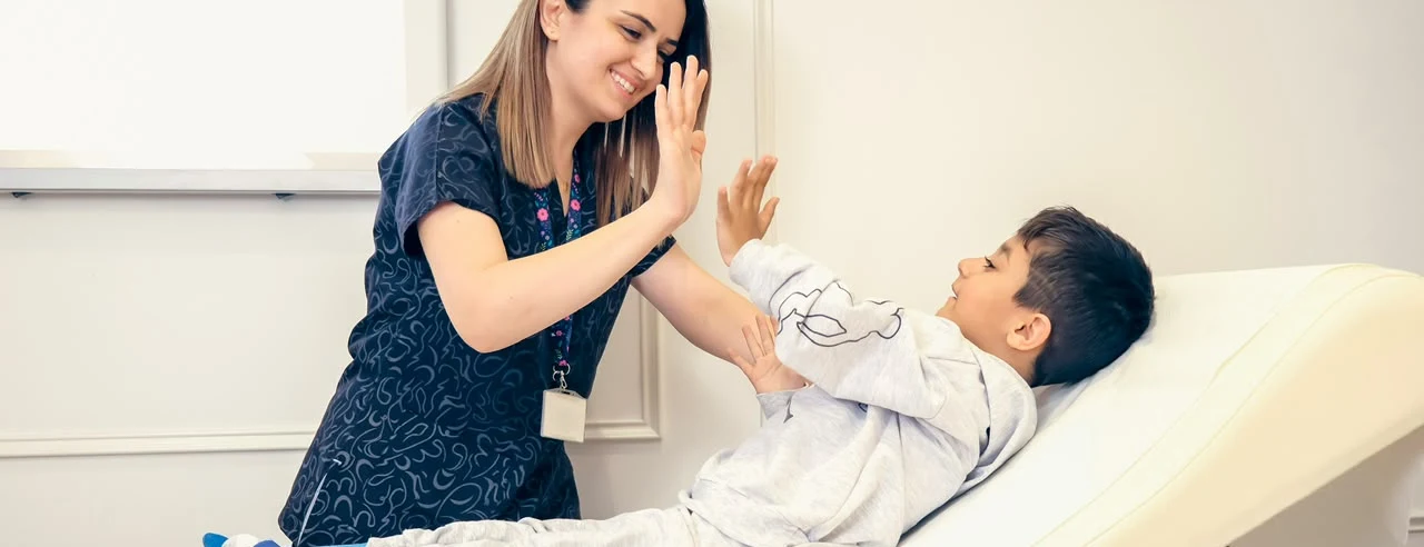 A nurse and a young patient sharing a high-five.